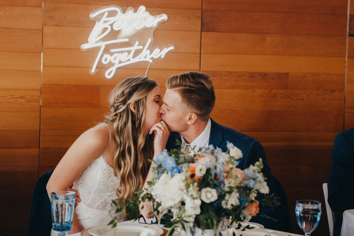 bride and groom kissing under the better together sign