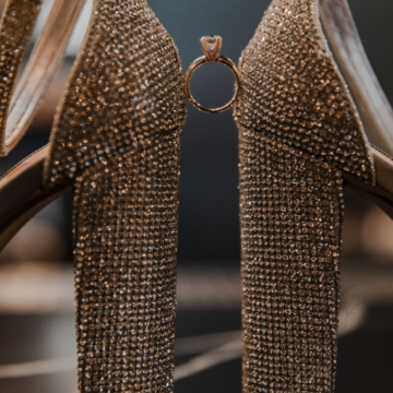 close up of a high heeled pair of shoes with a wedding ring sitting between them