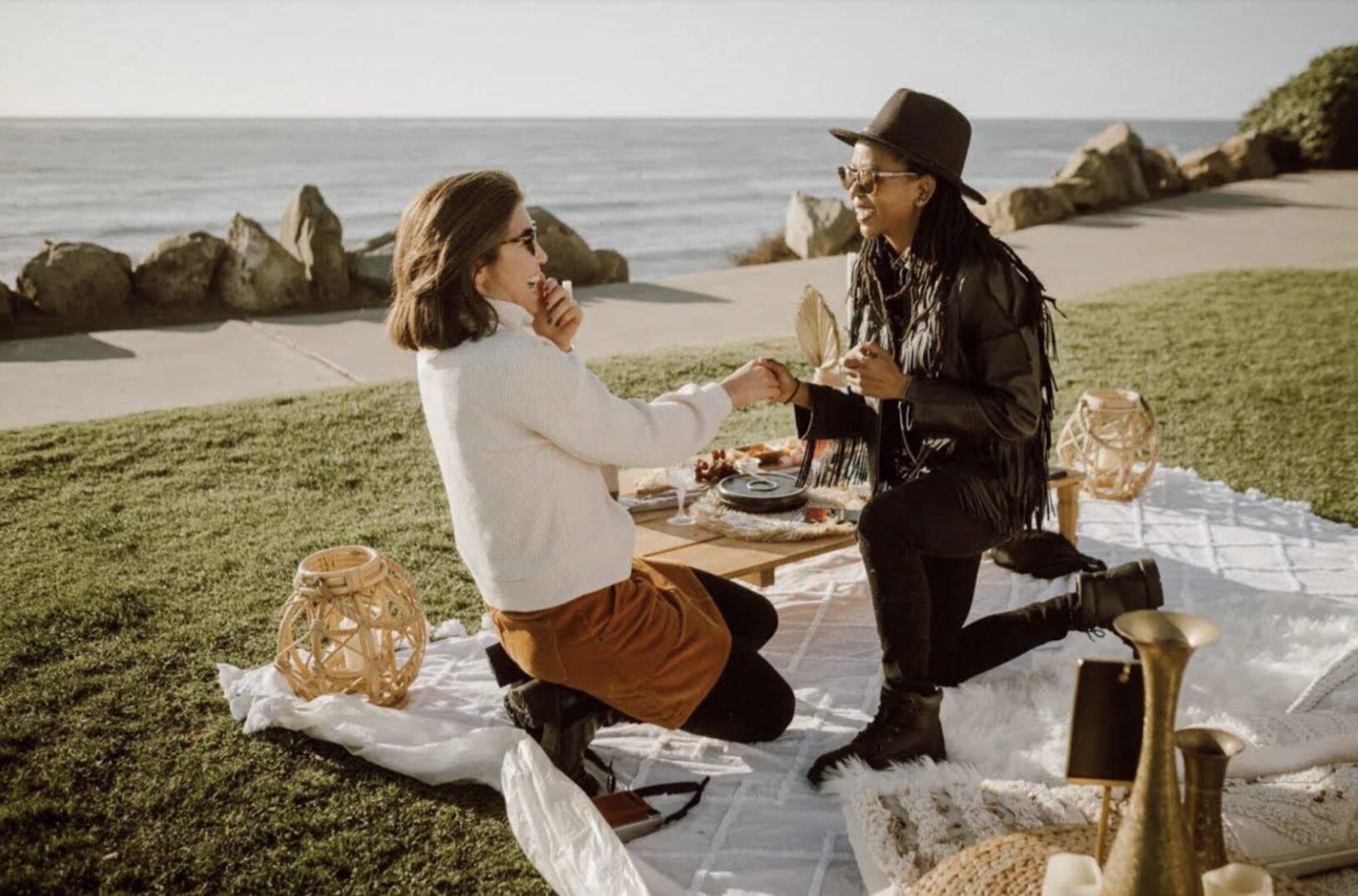Man proposing to a woman on a blanket near the ocean, enjoying a peaceful moment together.