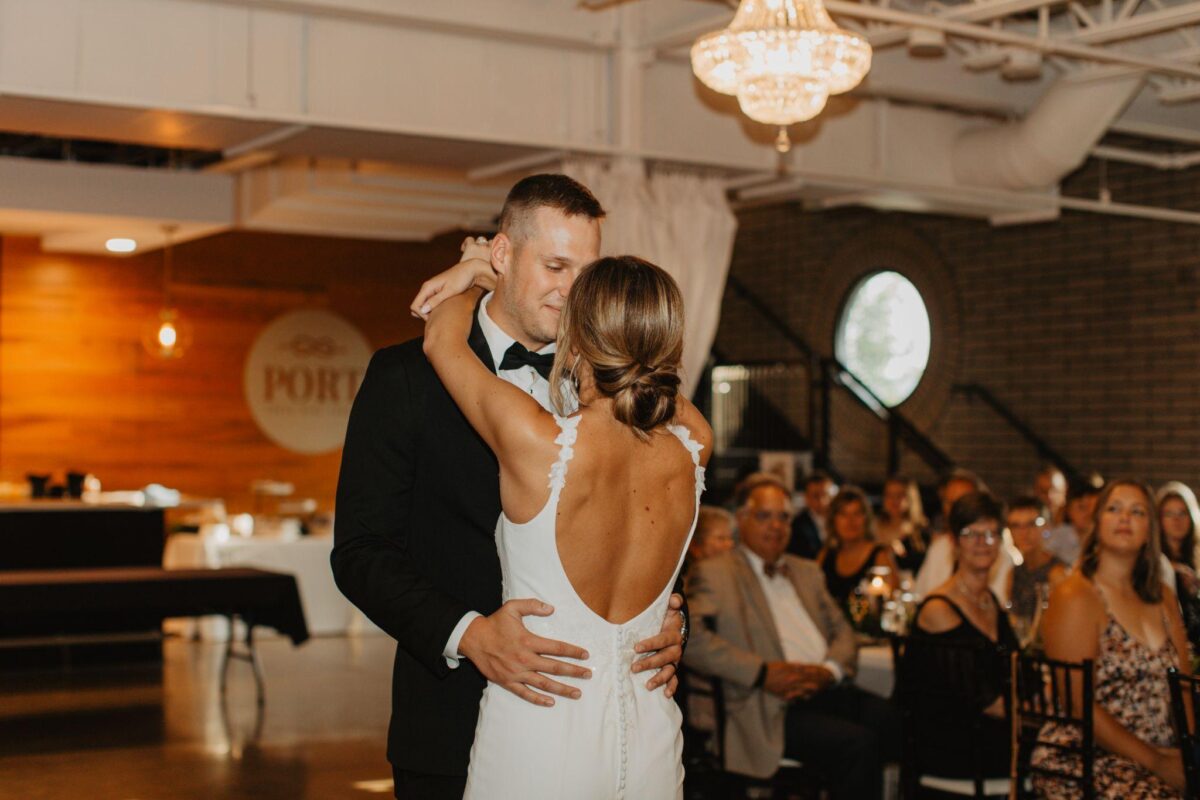 Bride and groom dancing, revealing the back of the bride's dress. Melodies of Love: Crafting Your Perfect First Dance Playlist.