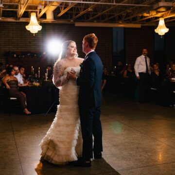 Newlyweds share their first dance at wedding reception, surrounded by love and joy.