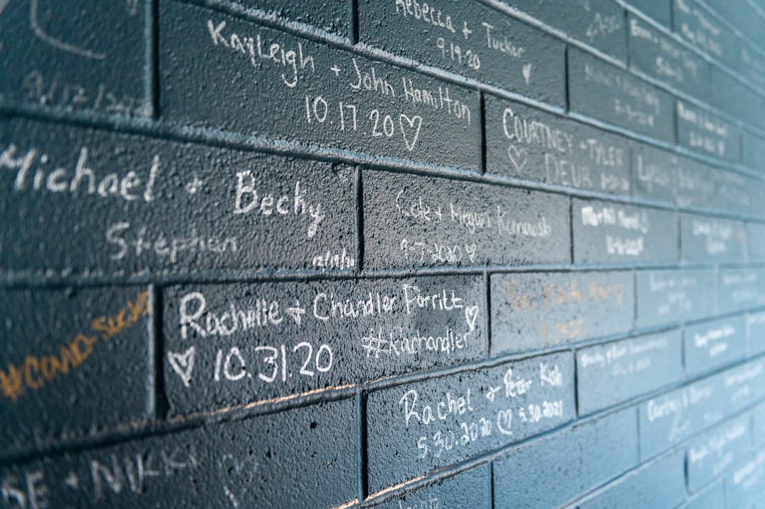 a wall covered in names and dates by brides and grooms who got married at port 393